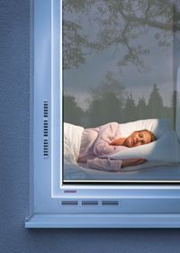 Frau schläft hinter Fenster mit I-tec-Lüftung, Internorm