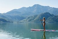 Frau auf Bord auf See, Stand-Up-Paddling auf dem See, Stand-Up-Paddlerin auf See vor Bergkulisse, Tourist Information Kochel a. See