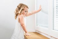 Mädchen vor Fenster mit integriertem Sonnenschutz, Internorm