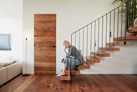 Frau sitzt auf Holztreppe, Frau auf Treppe, Innenraum mit Holzfußboden, Holztreppe und Holztür,  Josko Smart Mix, Josko