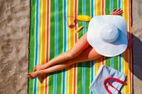 Frau mit Sonnenhut auf buntem Strandtuch, I.D. Riva Tours