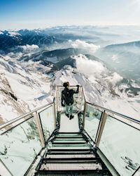 Mann auf gläserner Aussichtsplattform, spektakuläres Bergpanorama, Aussichtsplattform aud Glas, Ausblick auf schneebedeckte Gipfel, Alpenpanorama, Schladming-Dachstein, 