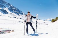 Frau mit Skiern im Schnee vor Bergkulisse, Intersport