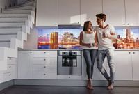 Paar in Küche mit beleuchteter Arbeitsplattenrückwand, Glasrückwand Motiv Skyline, Glasprinter